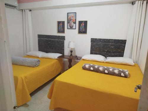two beds in a room with yellow sheets at Hotel El Almendro in Pedernales