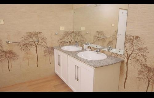 a bathroom with two sinks and trees on the wall at Cs white house negombo in Negombo