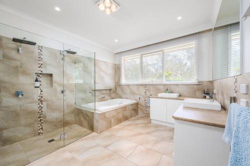 a bathroom with a shower and a tub and a sink at Serene Retreat 3 Cottages with Pool and Mountain Views in Wonga Park