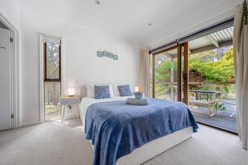 a bedroom with a bed and a large window at Country Charm Cottage with Pool and Forest Views in Wonga Park