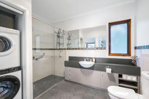 a bathroom with a sink and a washing machine at Country Charm Cottage with Pool and Forest Views in Wonga Park