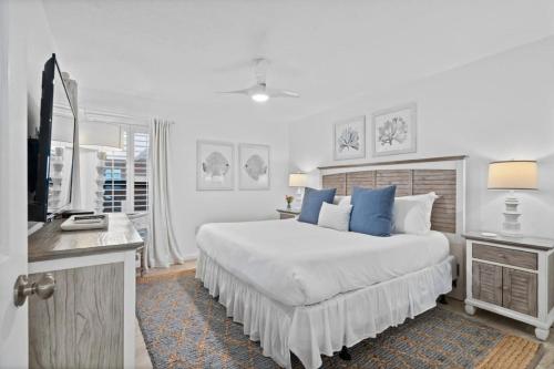 a white bedroom with a large bed with blue pillows at Jetty East, Paradise Palms, Sleeps 4, Pool Private Beach in Destin