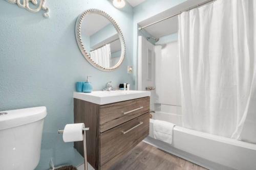 a bathroom with a sink and a tub and a mirror at Cozy beach bungalow close to ocean with large yard in Galveston