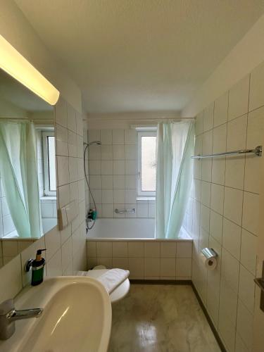 a white bathroom with a tub and a sink at Basic Flat with Balcony in Zurich in Zurich