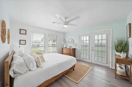 a white bedroom with a bed and a ceiling fan at Bright and Cozy 4 Bedroom close to the Ocean in Galveston