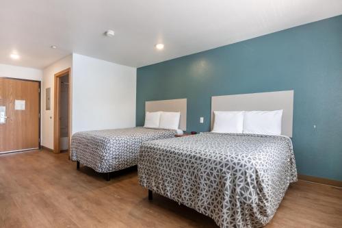 two beds in a room with blue walls and wooden floors at Woodspring Suites Huntsville/ Madison in Madison