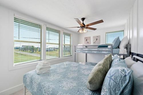 Un dormitorio con una cama y un ventilador de techo. en Cute beach house with large deck and fire pit, close to the beach, en Galveston