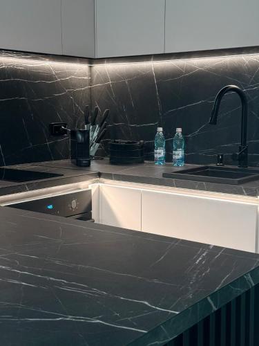 a kitchen with a black counter top with two bottles of water at Adora Park Exclusive Stay in Arad