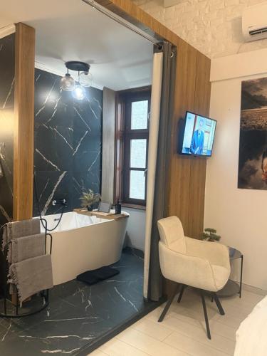 a bathroom with a tub and a chair and a television at Lux Dabich 2 in Novi Sad