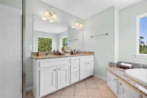 Stunning bayfront home with spacious deck and incredible Galveston Bay views في Shoreacres: حمام به مغسلتين ومرآة كبيرة