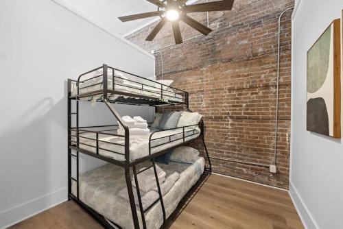 a room with two bunk beds in front of a brick wall at Historic Downtown Galveston Flat With Game Room in Galveston