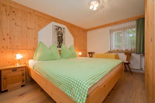Schlafzimmer mit einem Bett mit einer grünen und weißen Bettdecke in der Unterkunft Haus Waldrand in Oberndorf in Tirol