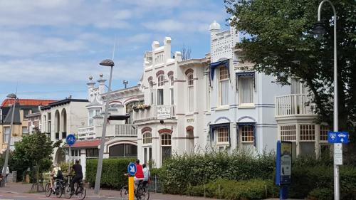 a white building with people riding bikes in front of it at Hendrika Apartments in Zandvoort