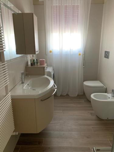 a white bathroom with a sink and a toilet at Calipso in Abano Terme