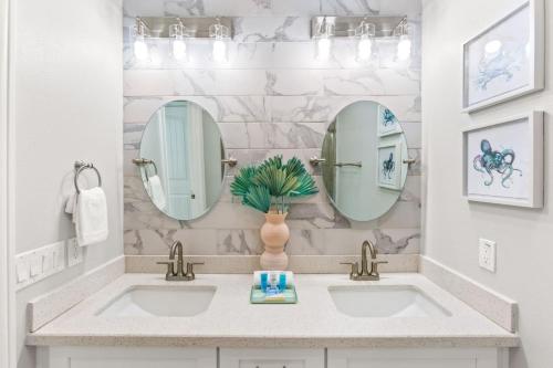 a bathroom with two sinks and two mirrors at Family Friendly 3-Bedroom Coastal Escape in Galveston