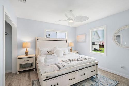 ein weißes Schlafzimmer mit einem Bett und zwei Nachttischen in der Unterkunft Beach bungalow with large, wrap-around deck, close to beach in Galveston