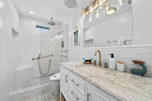 a white bathroom with a sink and a shower at Waterfront beach house with the ultimate game room and two docks in Oyster Creek
