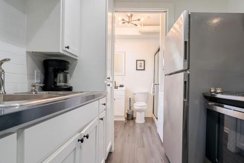 La cuisine blanche est équipée d'un évier et d'un réfrigérateur. dans l'établissement Historic charmer close to all the beach and strand, à Galveston