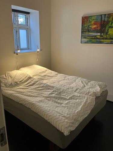 an unmade bed in a room with a window at Gården in Sønder Felding
