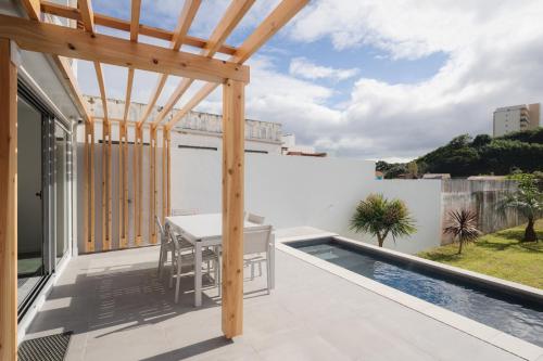 a roof deck with a table and a pool at Figueiras House Pópulo Beach in Ponta Delgada