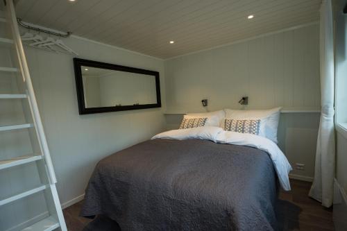 Un dormitorio con una cama con un espejo en la pared. en Krøgeneslåven Microtel, en Arendal