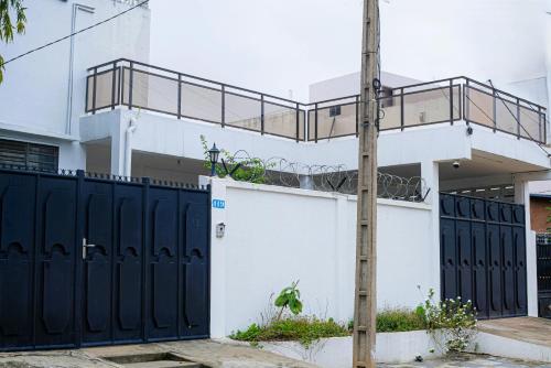 a white house with black gates and a fence at Villa meublée Fidjrossè, Cotonou in Cotonou