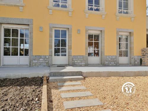 a yellow building with doors and a walkway at La Maison du Bourg, 4 personnes in Louverné