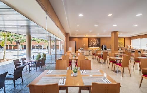 サン・セバスティアン・デ・ロス・レイエスにあるSercotel de los Reyesの木製のテーブルと椅子と窓のあるレストラン