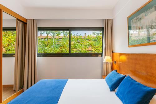 a hotel room with a bed and two windows at Sercotel de los Reyes in San Sebastián de los Reyes