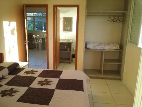 a bedroom with a bed and a bathroom with a sink at Pousada e Camping Lagoa da Conceição in Florianópolis