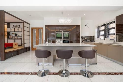 een keuken met een groot eiland met twee barkrukken bij Exceptional Luxury w Leisure Facilities in Teddington