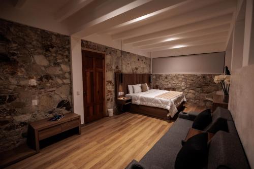 a bedroom with a bed and a stone wall at Hotel Tabáa Oaxaca in Oaxaca City