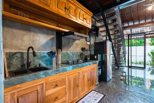 a kitchen with wooden cabinets and a sink at Weda Ubud by Madhava Villas in Ubud