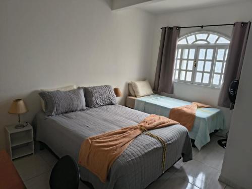 a bedroom with two beds and a window at Estadia Férias e Trabalho in Vila Velha