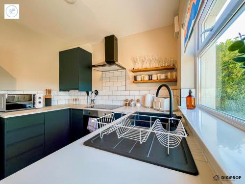 a kitchen with blue cabinets and a sink and a window at Alder House - Dowlais in Dowlais