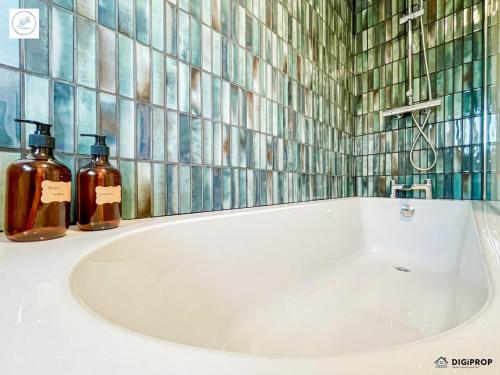 a bathroom with a bath tub with two bottles of soap at Alder House - Dowlais in Dowlais