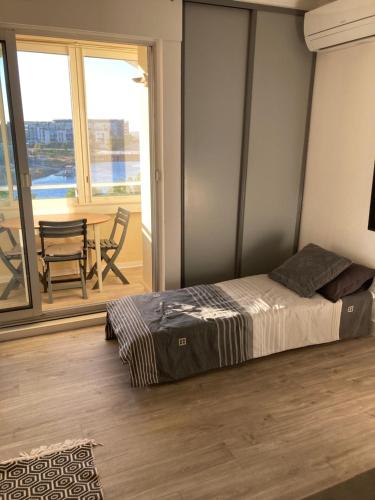 a bedroom with a bed and a balcony with a table at Studio belle vue in Sète