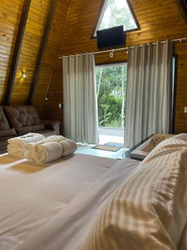 a large white bed in a room with a window at Chalé refúgio das águas in Ituporanga