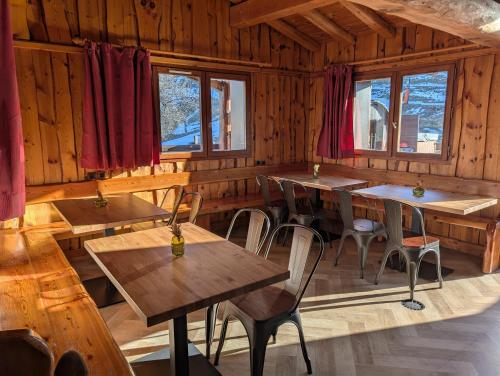 a restaurant with wooden tables and chairs and windows at Chalet MontBlanc in La Plagne Tarentaise