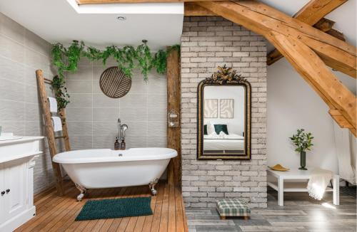 a bathroom with a white tub and a brick wall at Le Rooftop Loft premium 3 chambres avec terrasse & parking en centre-ville de Saint-Étienne in Saint-Étienne