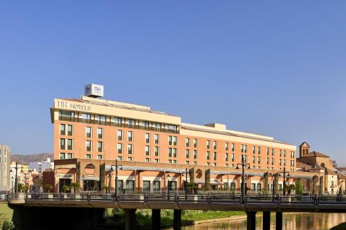 ein großes Gebäude auf einer Brücke über einen Fluss in der Unterkunft NH Málaga in Málaga