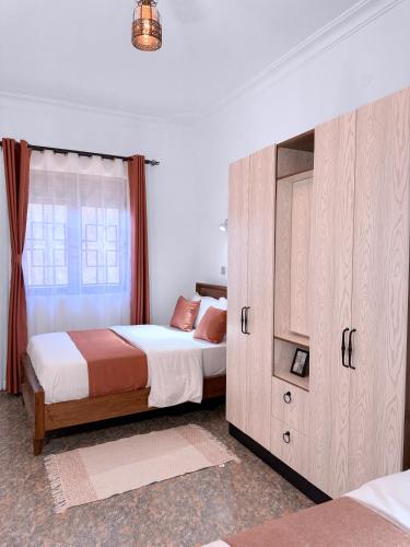 a bedroom with two beds and a large cabinet at Five-Eight Residences in Jinja