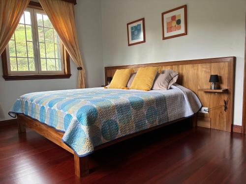 a bedroom with a large bed with a wooden headboard at Quinta das Palmeiras in Povoação