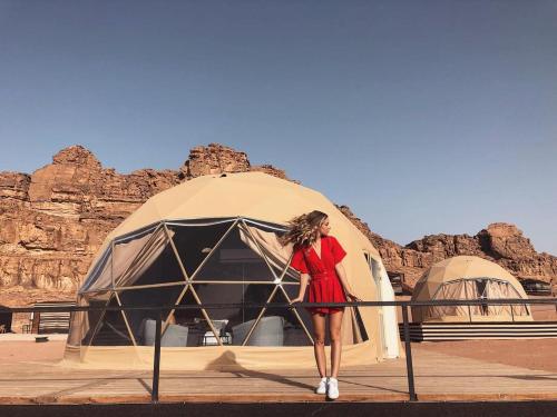 a woman in a red dress standing in front of a tent at magic rum hussen in Wadi Rum