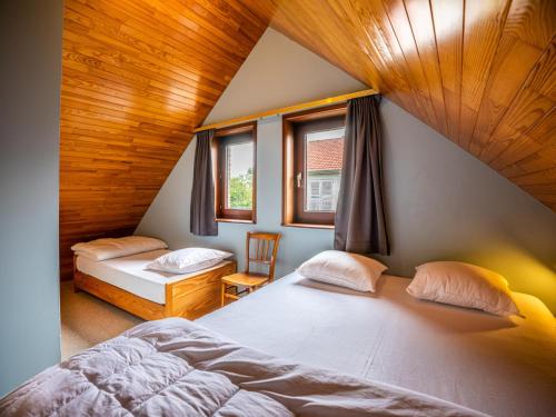 a attic bedroom with two beds and two windows at La Paix in Sint-Idesbald
