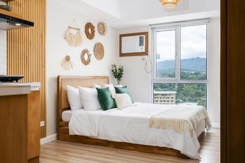 a bedroom with a bed with green pillows and a window at Virgo Nest Rentals - Avida Riala IT Park - City View in Tabok