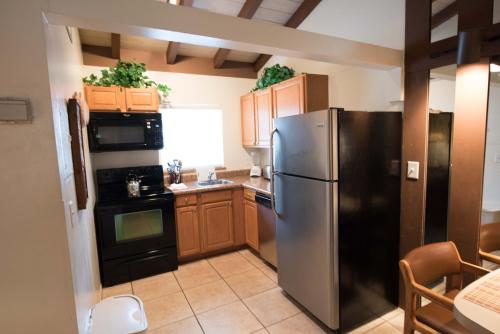 a kitchen with a stainless steel refrigerator and wooden cabinets at Sand Dune Shores, a VRI resort in Palm Beach Shores