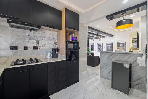 a kitchen with black cabinets and a counter top at Noir & Blanc Suite in Mama
