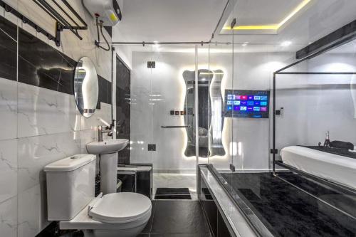 a bathroom with a toilet and a sink and a mirror at Noir & Blanc Suite in Mama