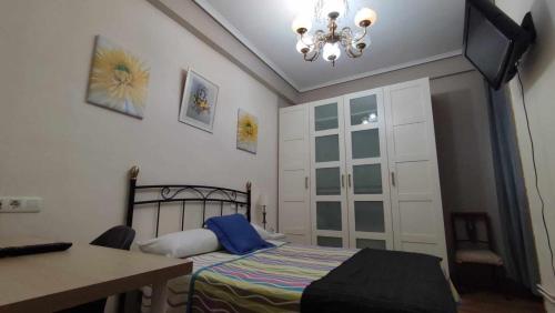 a bedroom with a bed and a desk and a chandelier at FlipHouse Rooms Pensión in Bilbao
